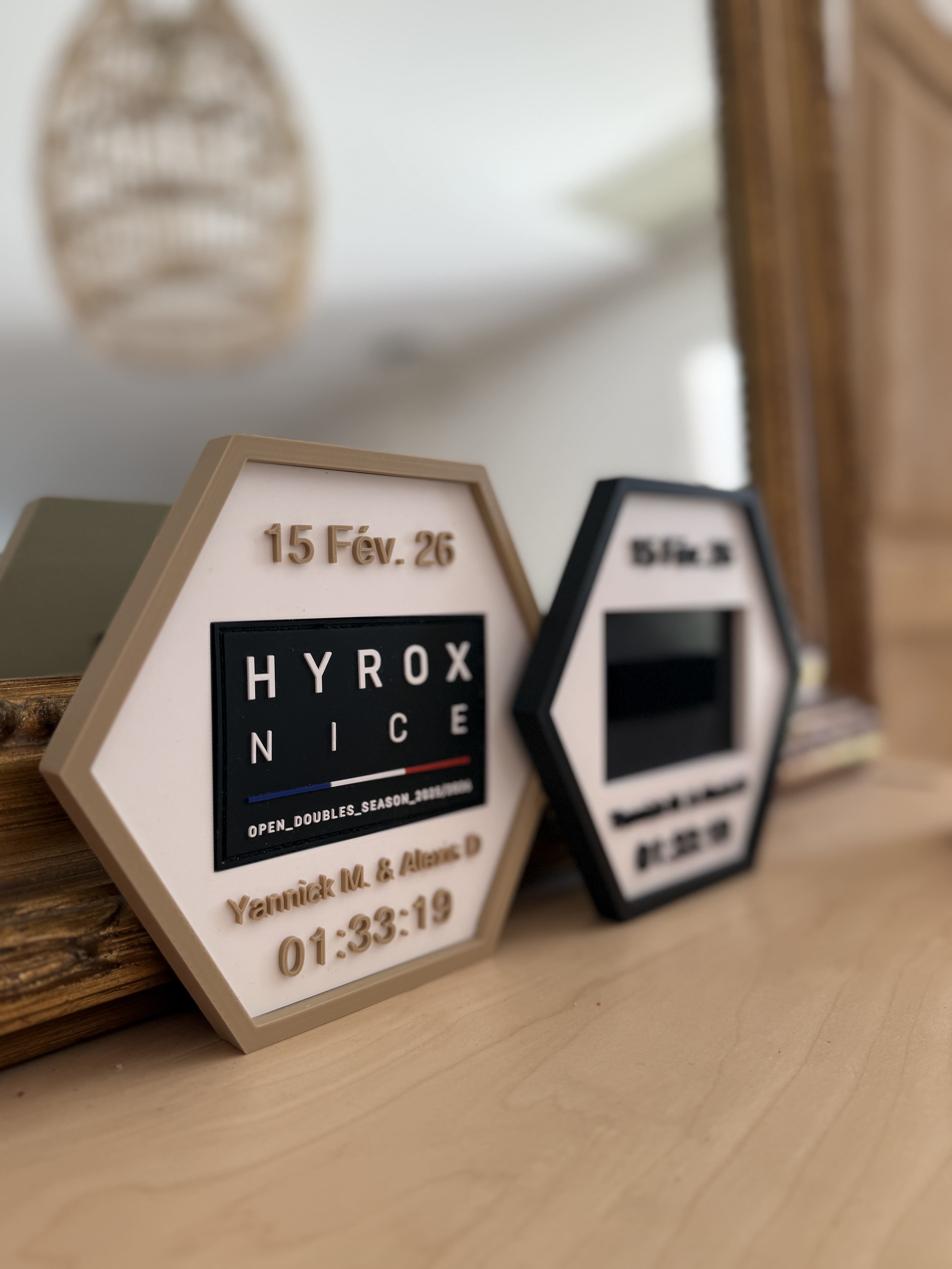 Two hexagonal ROXWALL frames holding HYROX finisher patches on a shelf