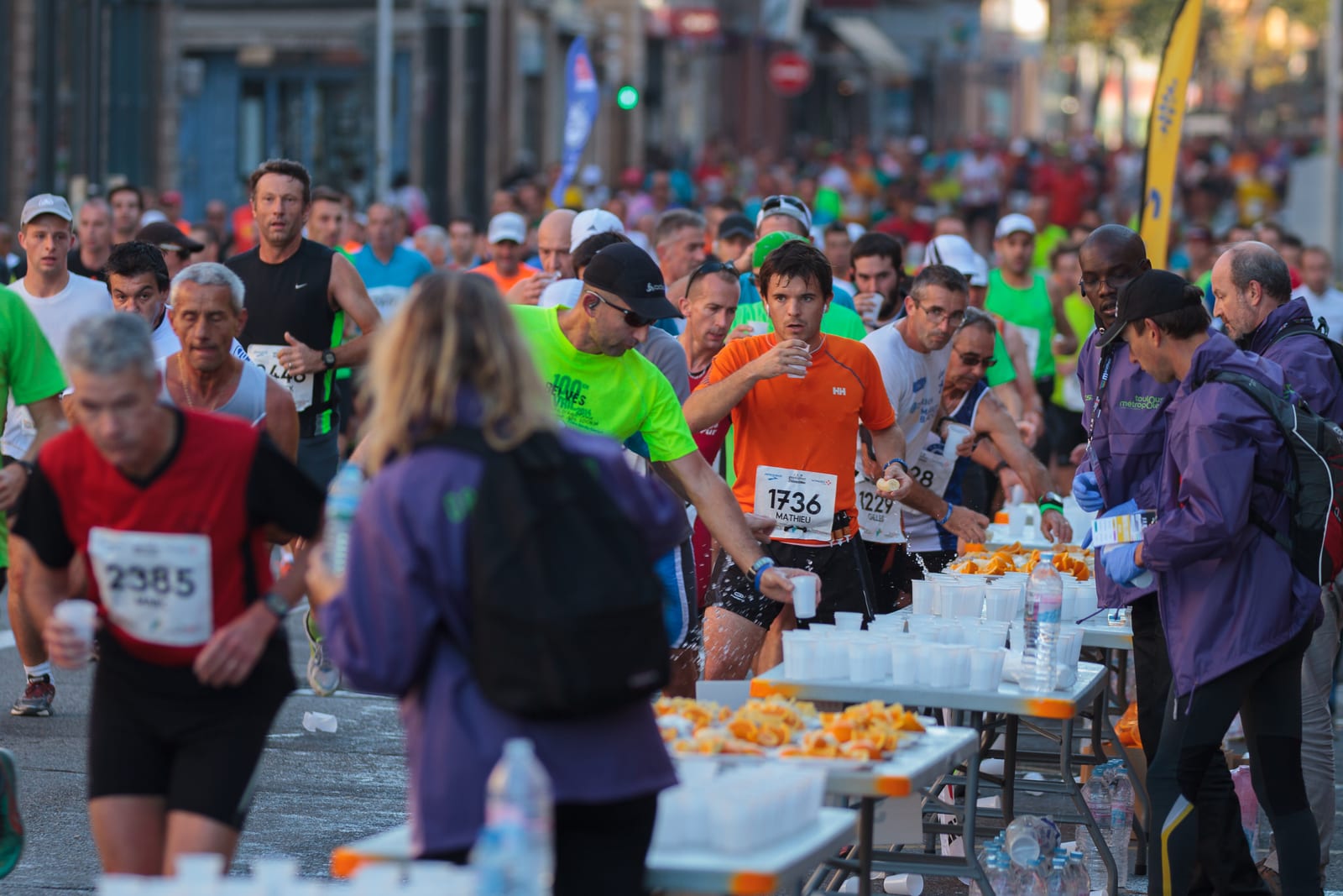 Runners taking water at a marathon aid station